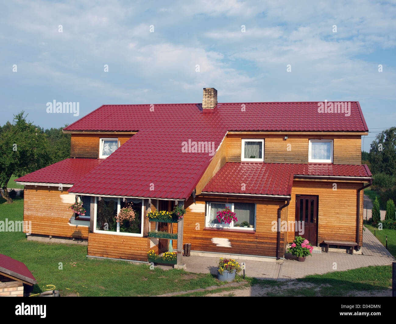 Maison de campagne avec des murs en bois et toit en métal rouge Banque D'Images