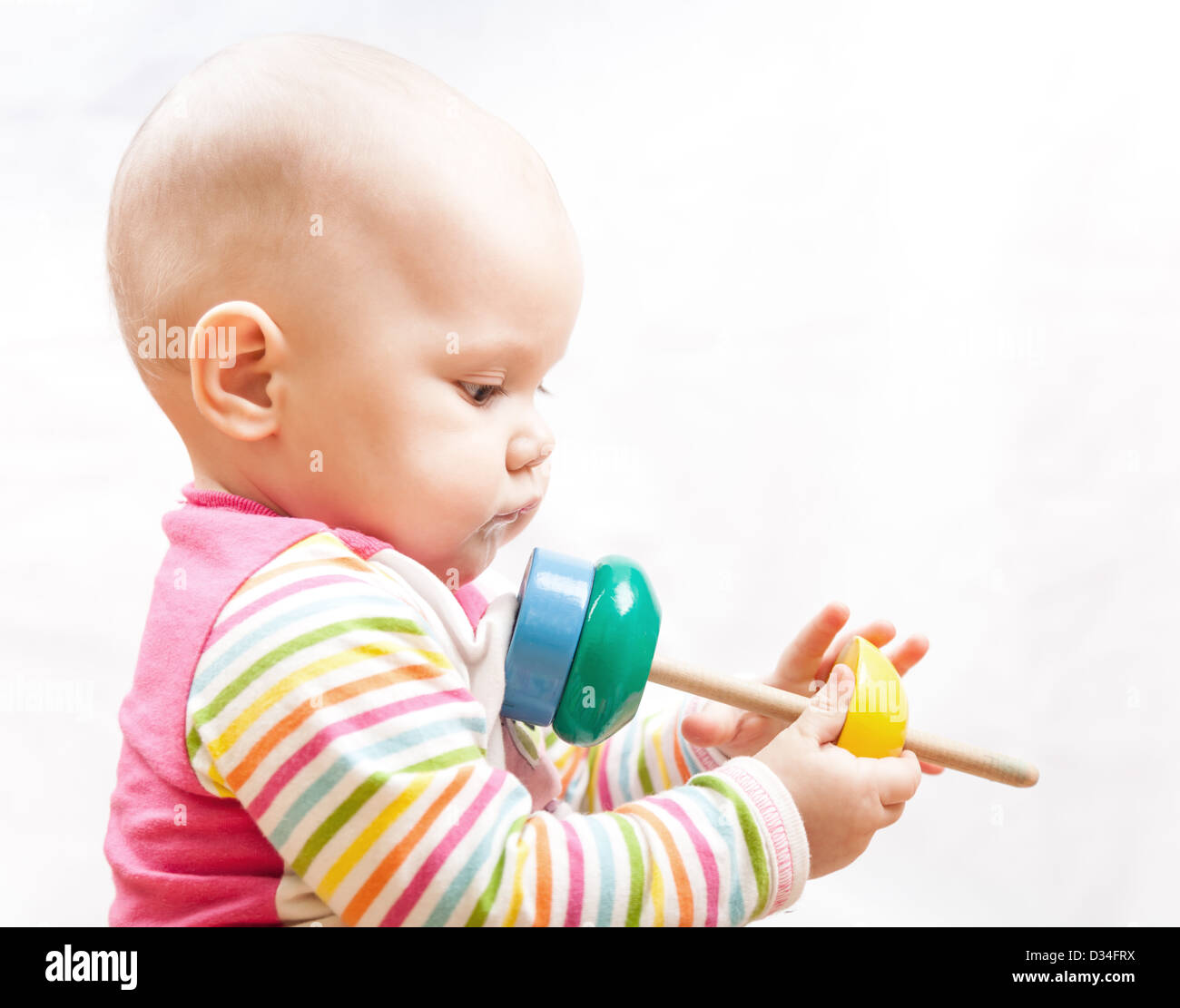 Peu triste brown eyed baby joue avec jouet en bois, portrait studio profile Banque D'Images