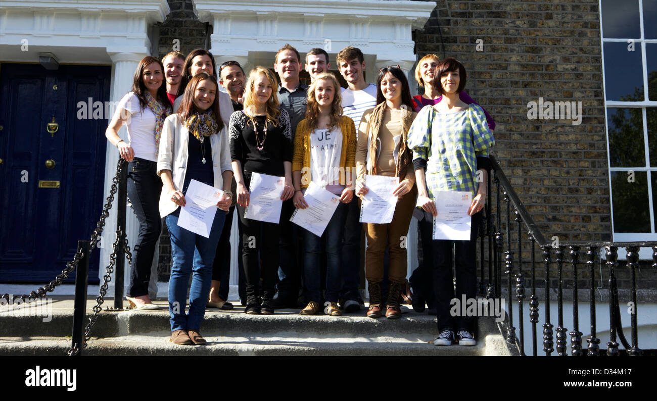 Classe du collège sur les marches d'une école avec leur diplôme en main Banque D'Images