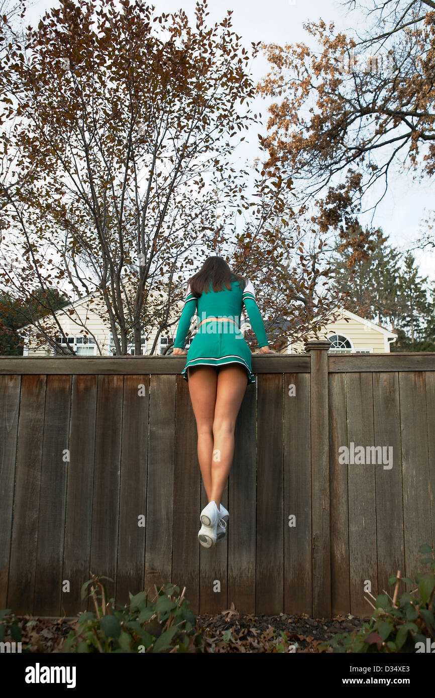 Cheerleader grimpe sur la clôture. Banque D'Images