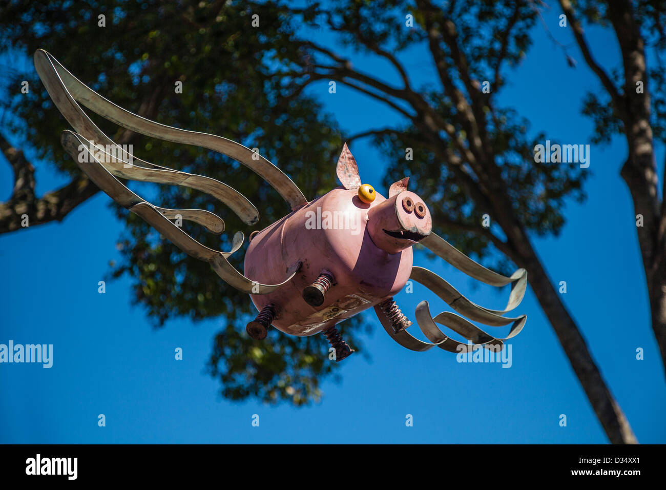 Une sculpture de métal d'un cochon volant se bloque à partir d'un arbre. Banque D'Images