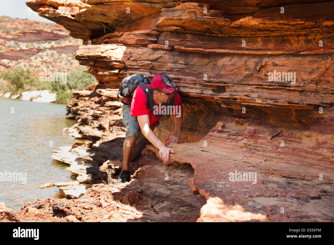 L'homme se faufiler le long du bord à pied boucle rock, le parc national de Kalbarri, Australie occidentale Banque D'Images