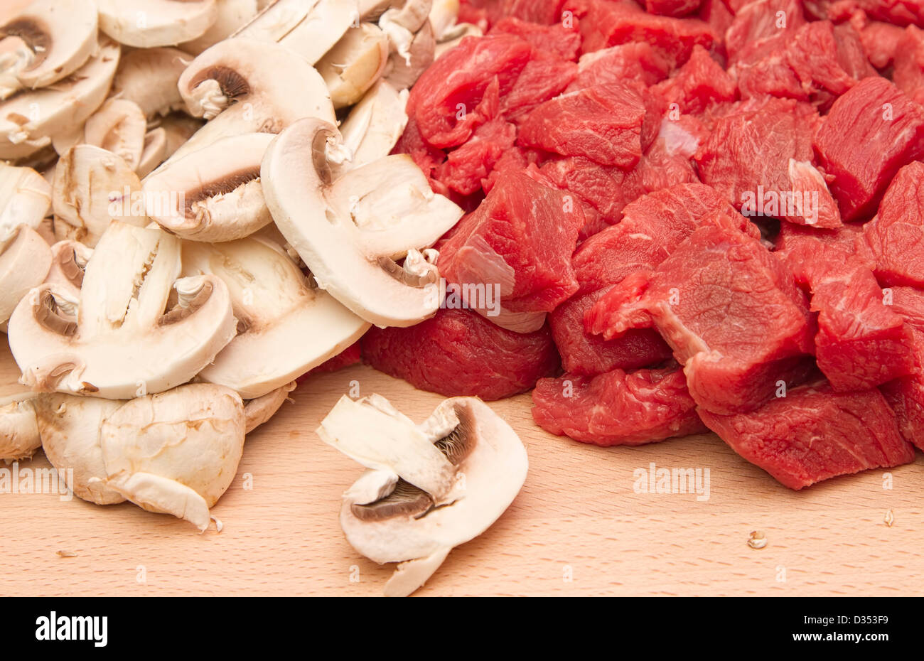 Steak de bœuf haché frais et champignons sur planche à découper en bois Banque D'Images
