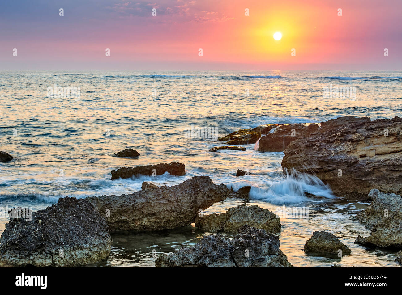 Coucher de soleil sur la mer avec des pierres sur le premier plan Banque D'Images