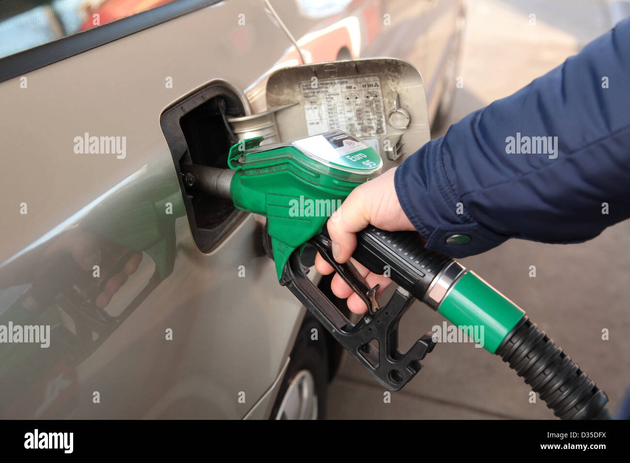 Un homme remplit sa voiture de carburant à une station-service Banque D'Images
