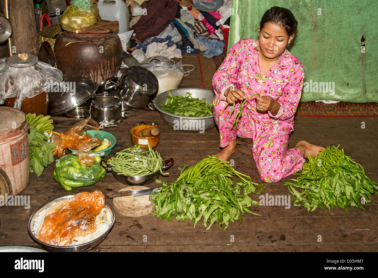 Jeune femme prépare des tiges de morning glory et épinards pour le dîner sur l'île de Koh Trong au Mékong de Kratie, au Cambodge Banque D'Images