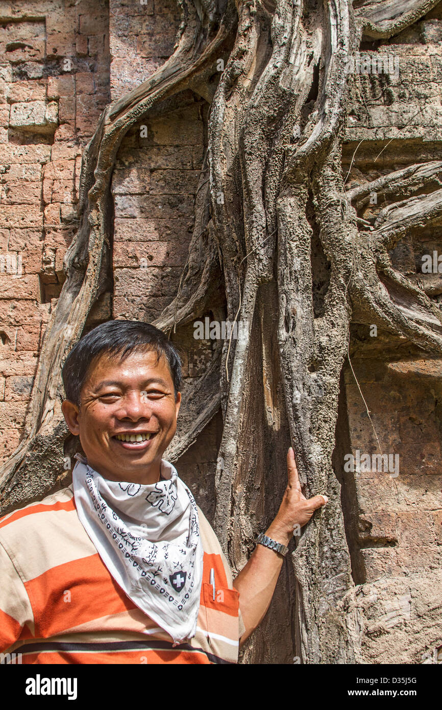 L'homme se distingue par racine de l'arbre à un temple à Sambor Prei Kuk, non loin de l'Angkor Wat complexe de ruines et de temples au Cambodge Banque D'Images