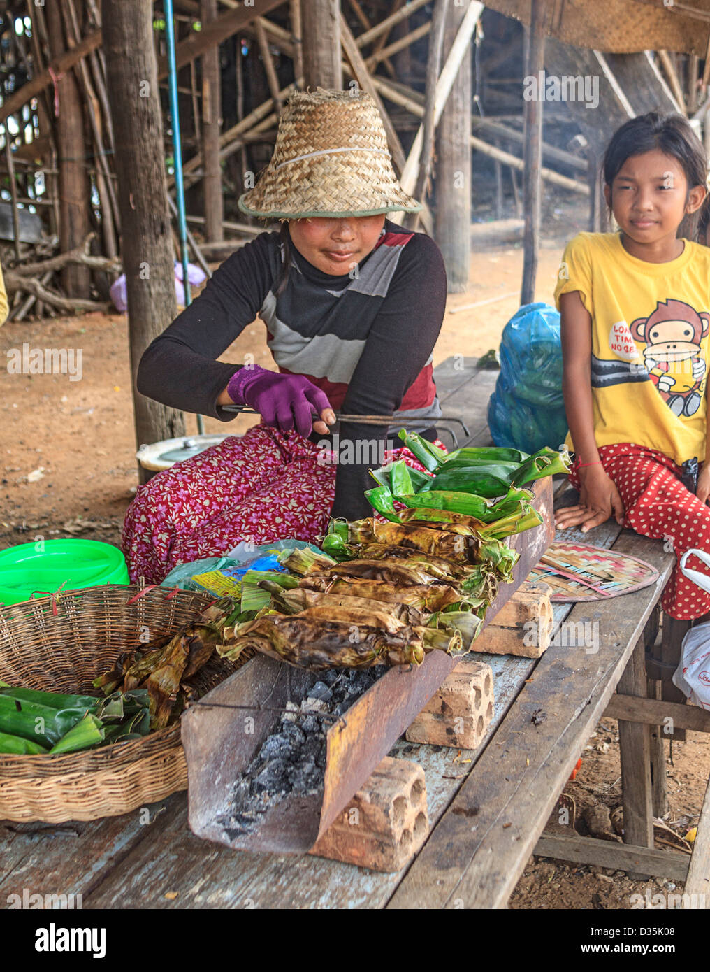Femme des barbecues les bananes dans des feuilles de bananier dans la région de Kompong Pluk (Phluk), un groupe de trois villages maison sur pilotis près de Siem Reap, Cambodge Banque D'Images