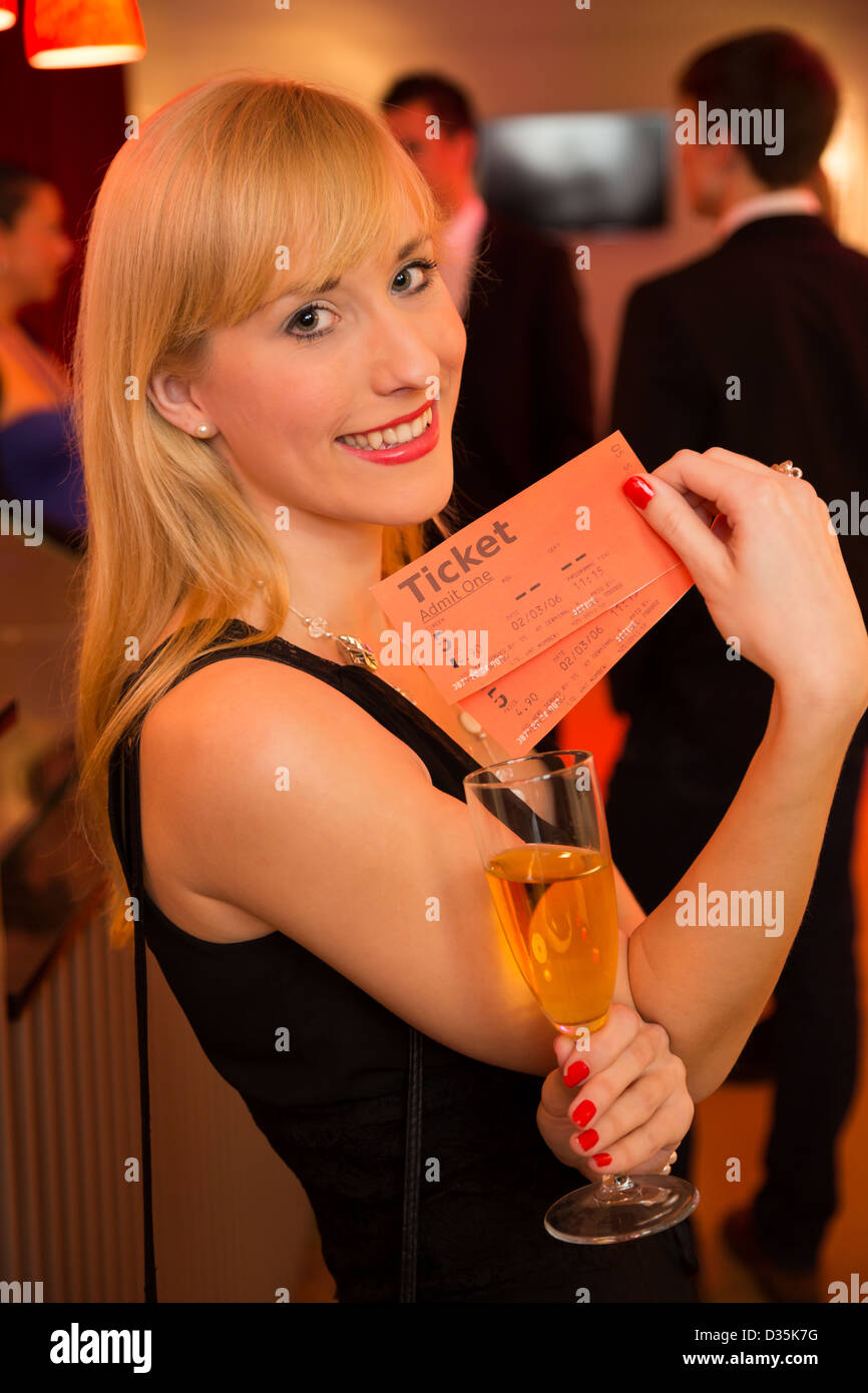 Belle femme présentant des billets ou des laissez-passer d'entrée de théâtre, de concert ou de cinéma Banque D'Images