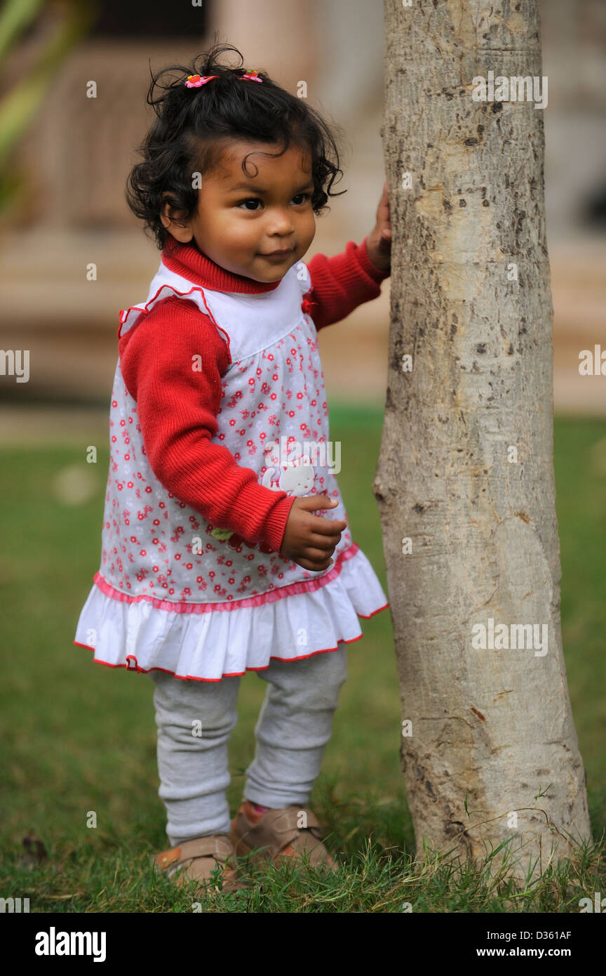 Bebe Fille Indienne Nid Permanent A Un Tronc D Arbre Dans Un Jardin Photo Stock Alamy