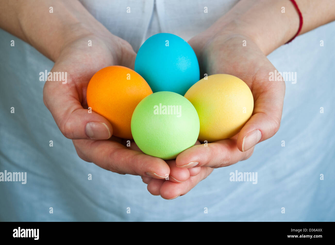 Les mains tenant quatre œufs de Pâques colorés Banque D'Images
