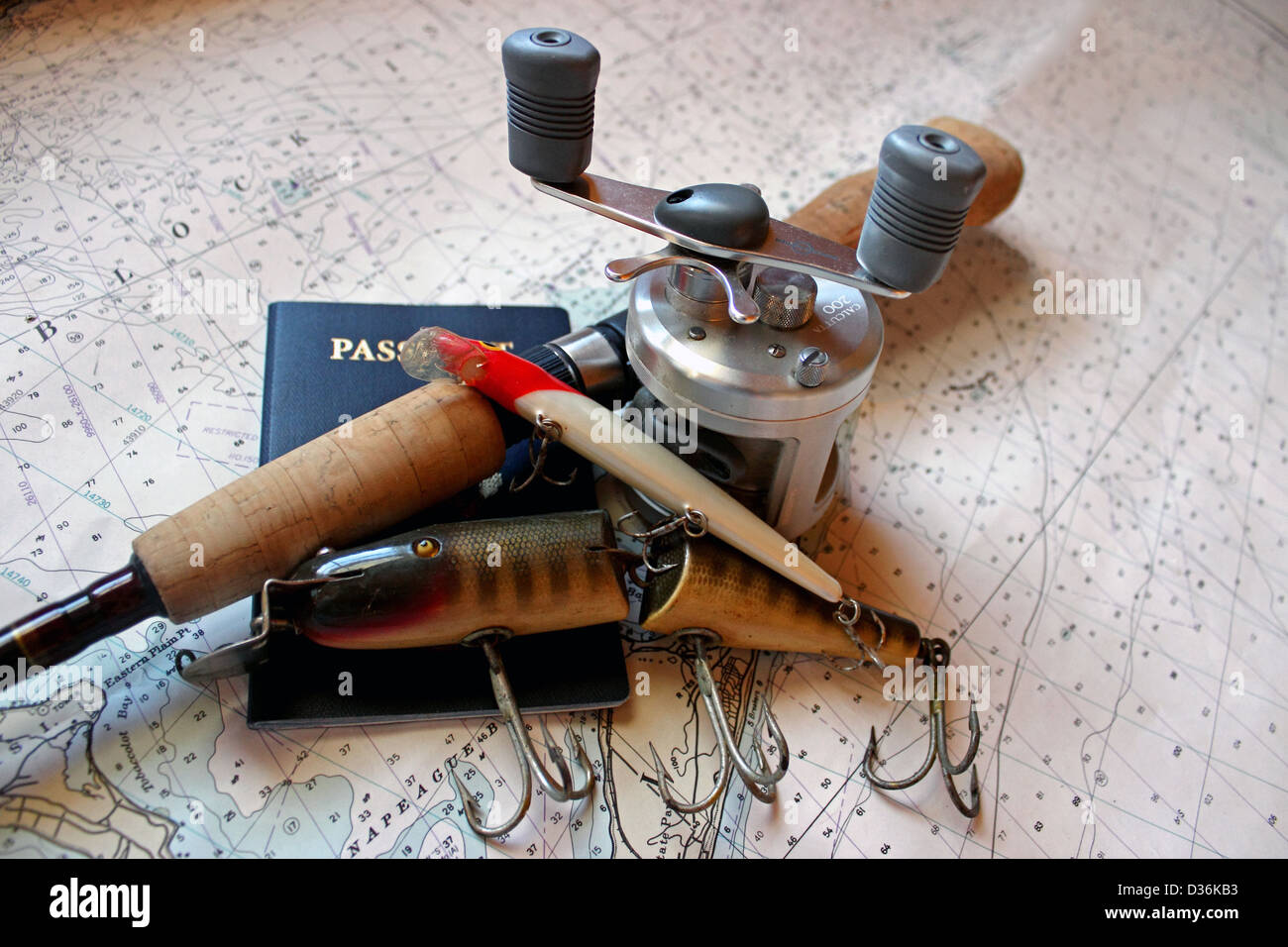 Une canne à pêche et appâts avec un passeport reste sur une carte marine. Banque D'Images Une canne à pêche et appâts avec un passeport reste sur une carte marine. Banque D'Images