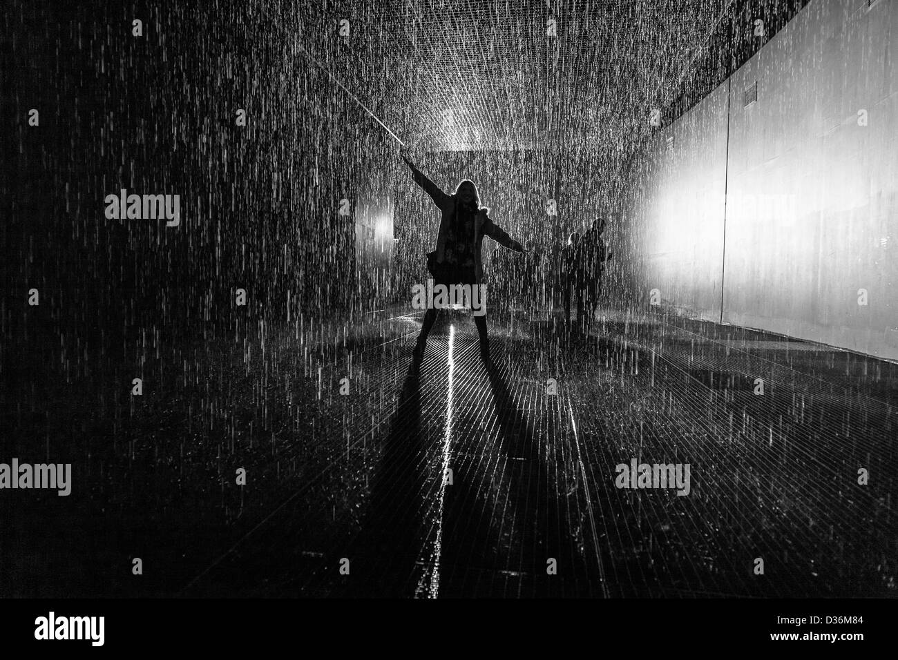 Femme debout avec les bras en l'air et les jambes sous la pluie avec la lumière venant de derrière pour créer d'ossature Banque D'Images