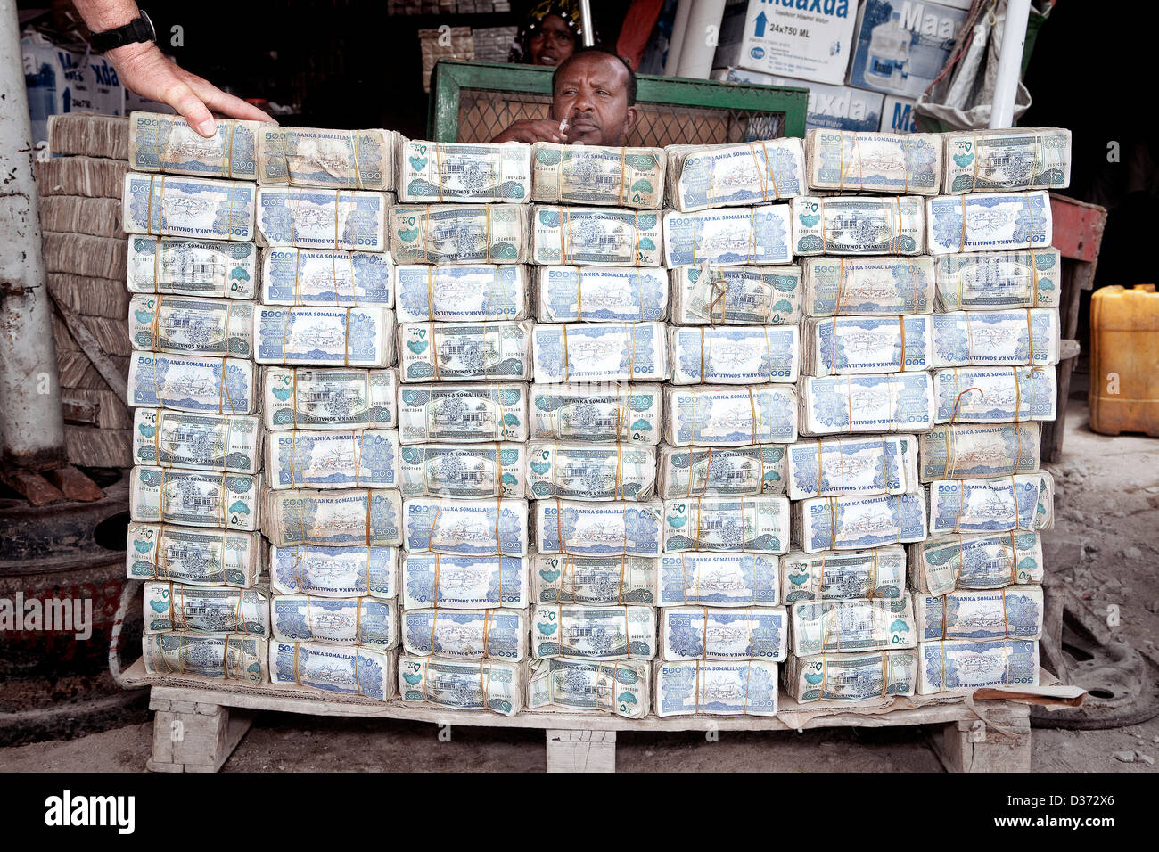 Un commerçant à l'échange d'argent en Hergeisa marché. Un touriste est de tenter de saisir un air taquin jeu de la monnaie locale. Banque D'Images