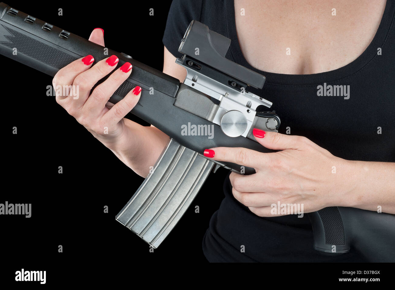 Femme avec de beaux ongles rouge tenant un fusil d'assaut noir et argent isolé sur noir. Banque D'Images