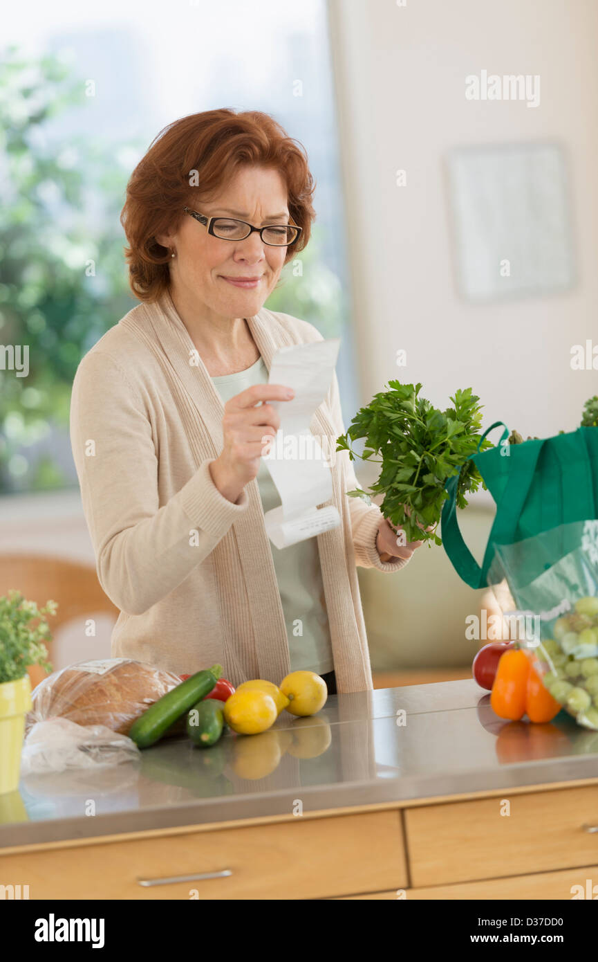USA, New Jersey, Jersey City, Senior woman reading liste de courses dans la cuisine Banque D'Images