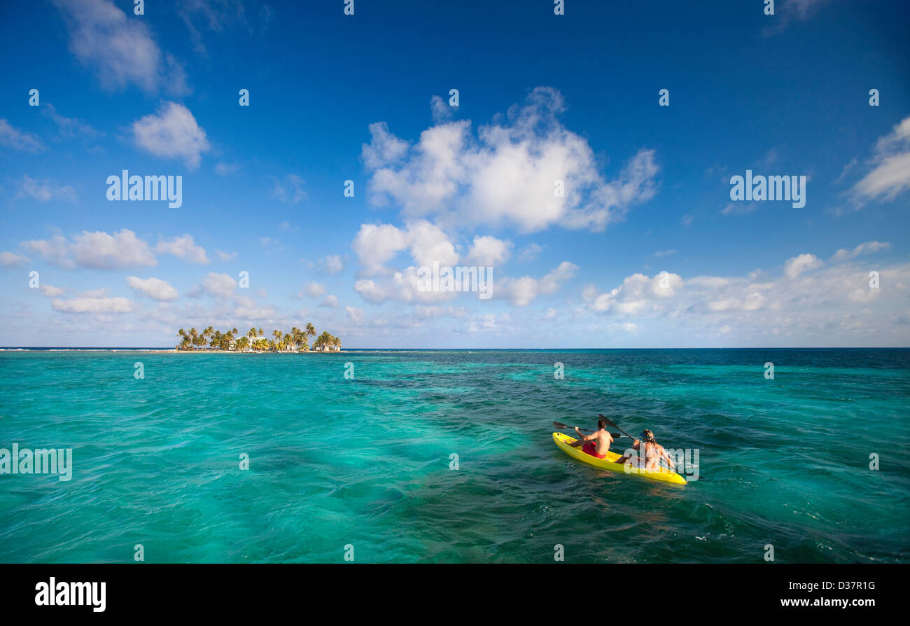 People rowing canoe in tropical water Banque D'Images
