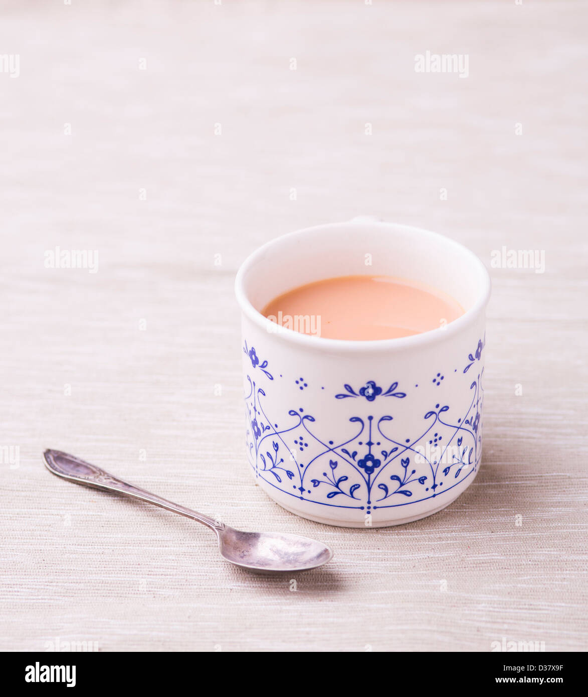 Tasse de Rooibos (buisson rouge) Thé au lait dans un service à la Chine avec une cuillère ancienne sur un fond neutre. Banque D'Images