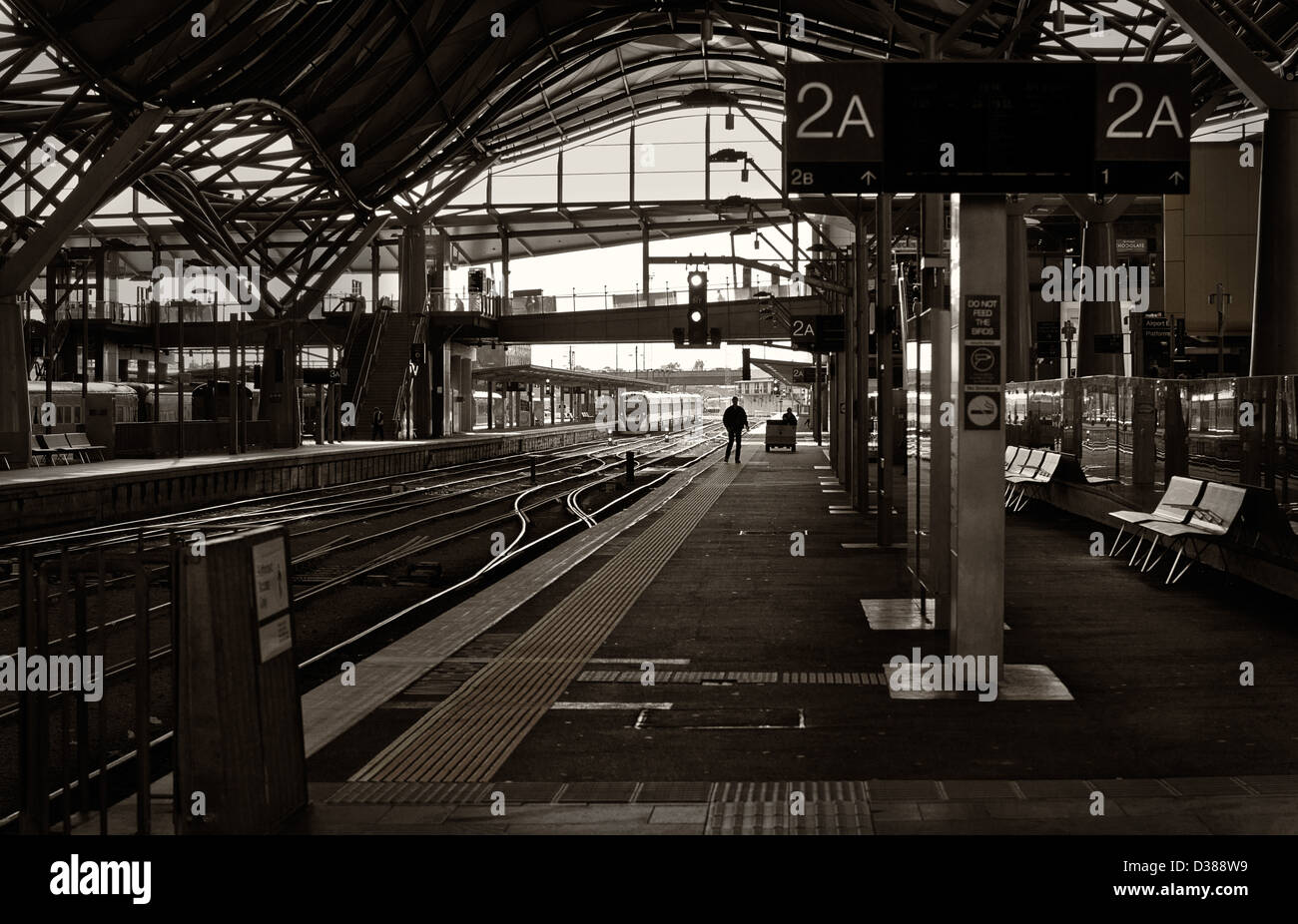 Le dirigeant d'une personne est découpé sur la lumière qu'il attend un train sur une plate-forme vide dans une gare ferroviaire. Banque D'Images