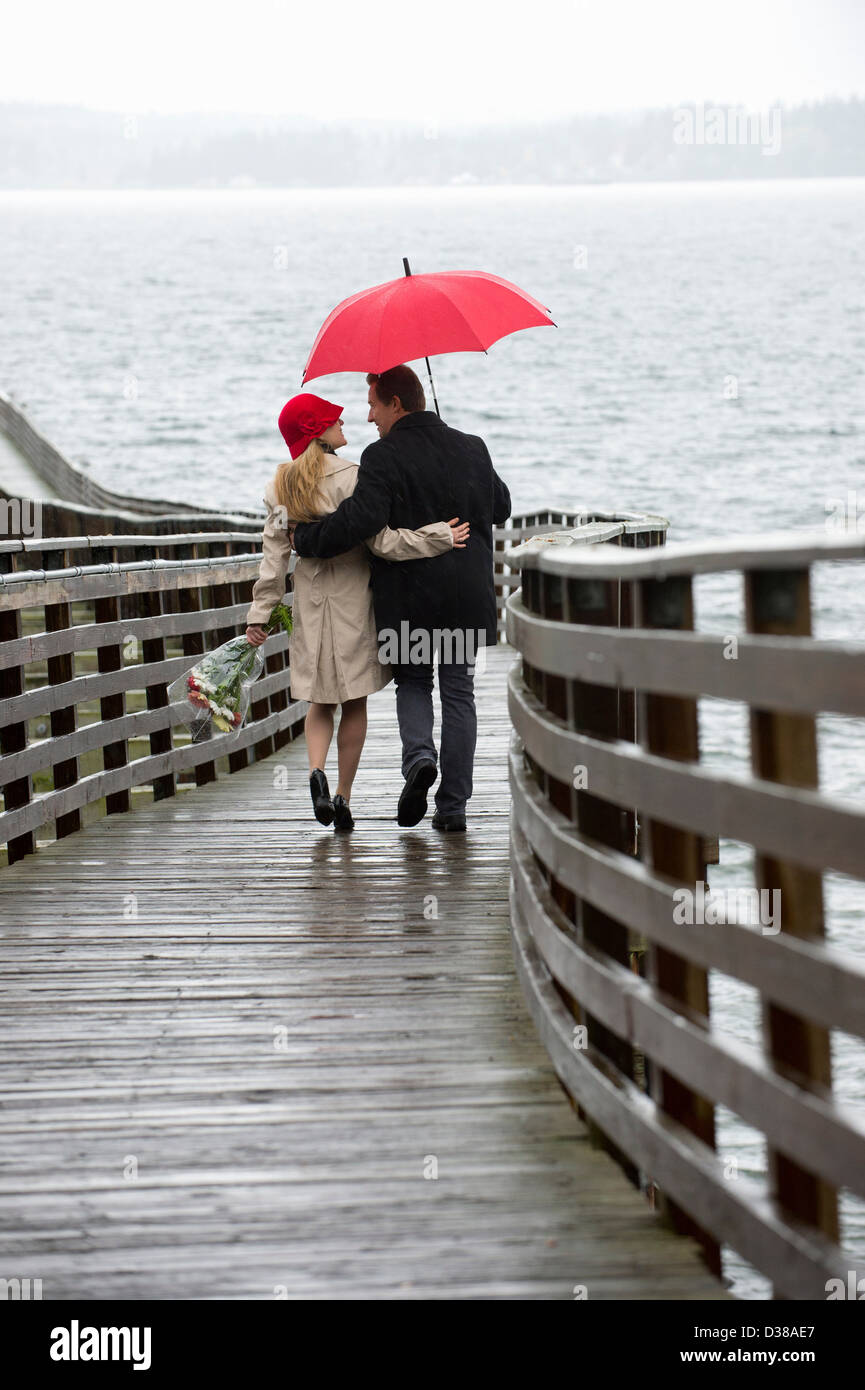 Couple en train de marcher sur la jetée en bois dans la pluie Banque D'Images