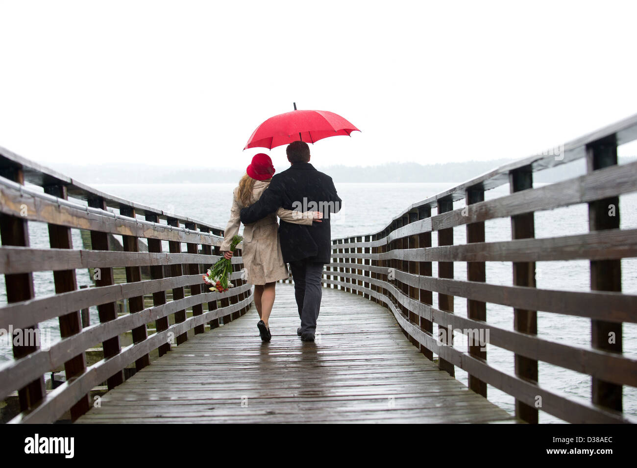 Couple en train de marcher sur la jetée en bois dans la pluie Banque D'Images