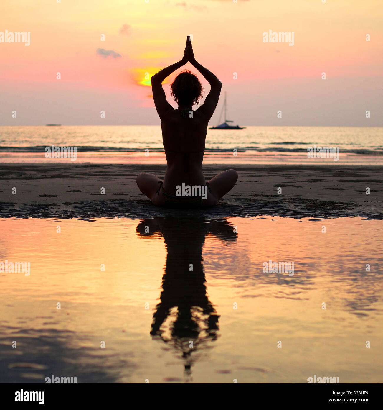 Yoga woman sitting in lotus pose sur la plage pendant le coucher du