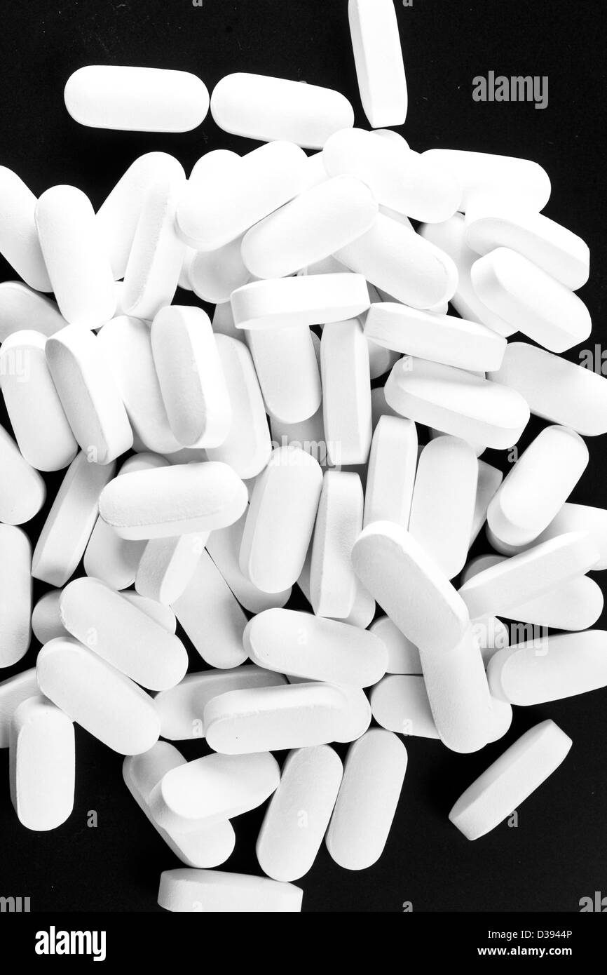Beaucoup de pilules blanches isolé sur noir. Photo en noir et blanc. Banque D'Images