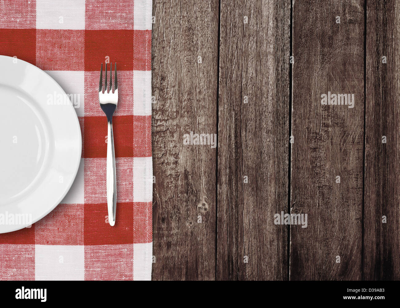 Plaque blanche et la fourche sur la vieille table en bois avec nappe rouge vérifié et copyspace Banque D'Images