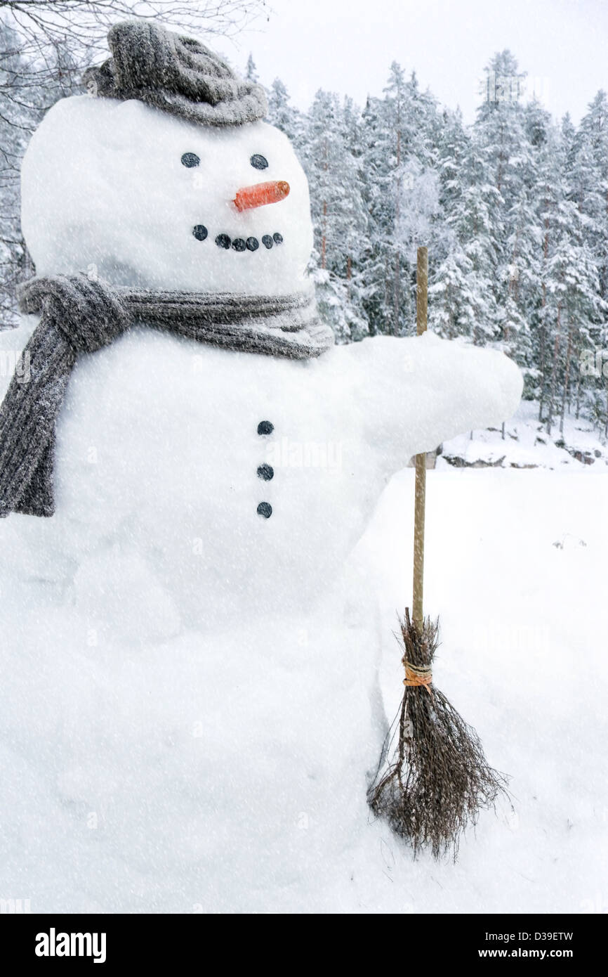 Le Snowman avec écharpe, chapeau et nez carotte en dehors des chutes de neige Banque D'Images