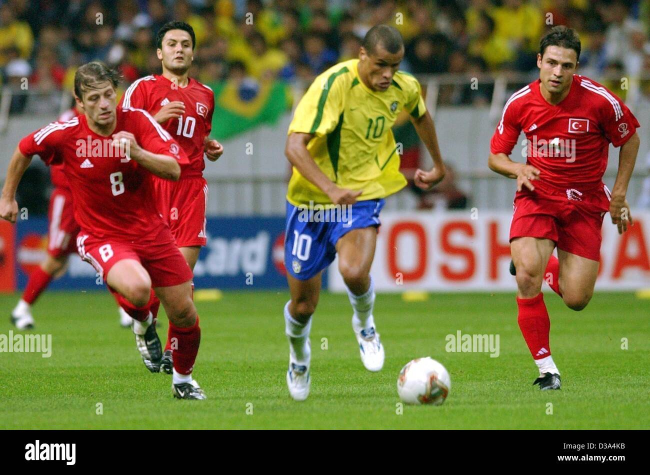 (Afp) - Le milieu de terrain brésilien Rivaldo (C) est chassé par les joueurs turc Tugay Kerimoglu (L), Yildiray Bastuerk et Fatih Akyel (R) au cours de la demi-finale dans le stade de Saitama, Japon, le 26 juin 2002. Le match s'est terminé 1:0 pour le Brésil, qui est qualifié pour la 7ème fois pour la finale de la Coupe du monde. Banque D'Images