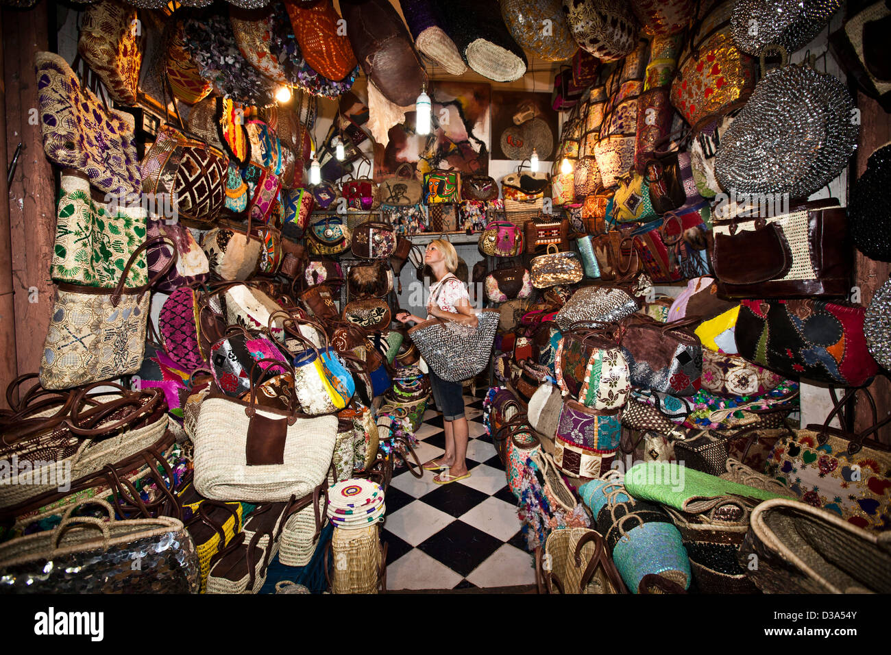 Jeune femme à la recherche de sacs au souk, Marrakech, Maroc Banque D'Images