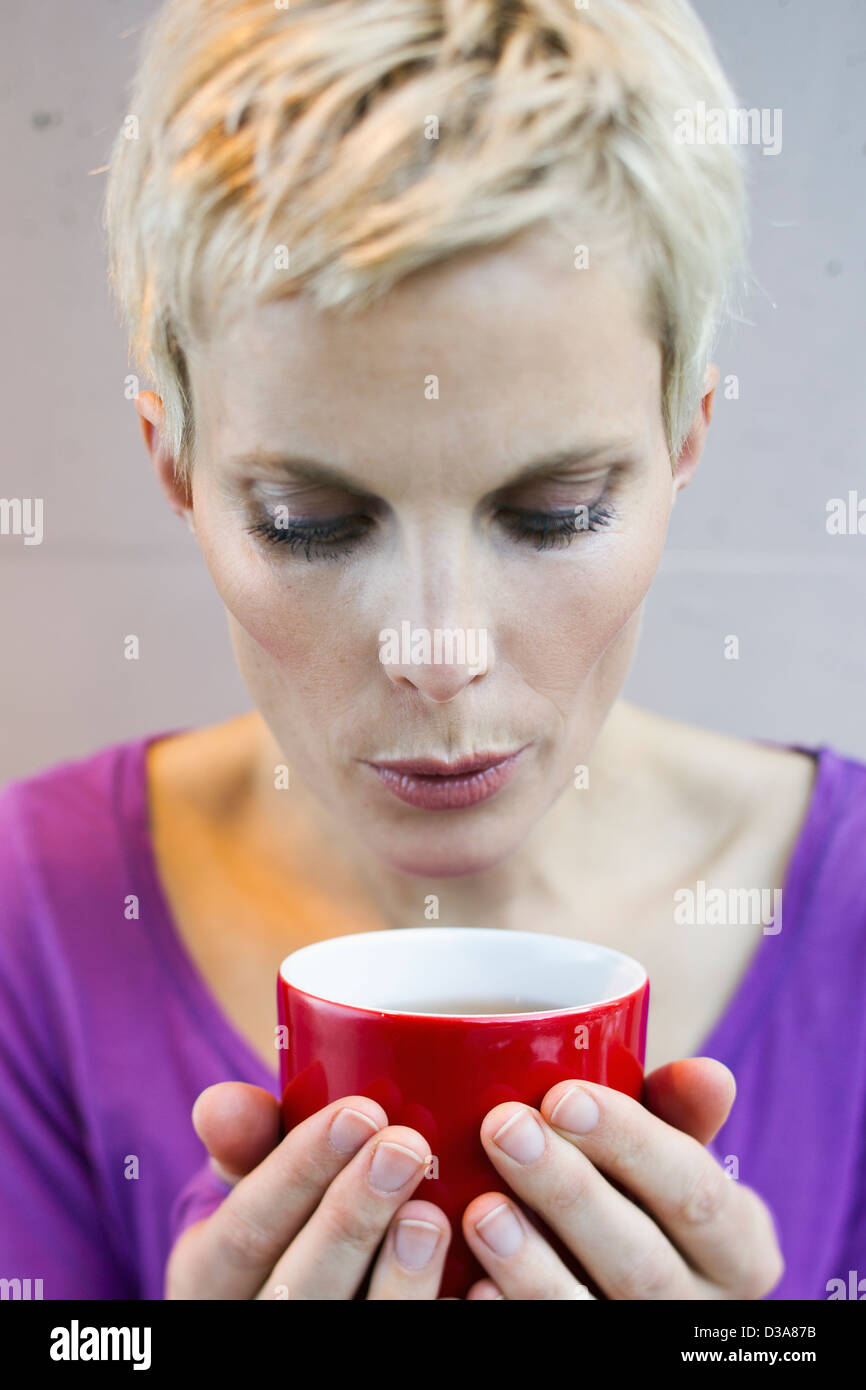 Smiling woman blowing sur tasse de thé Banque D'Images