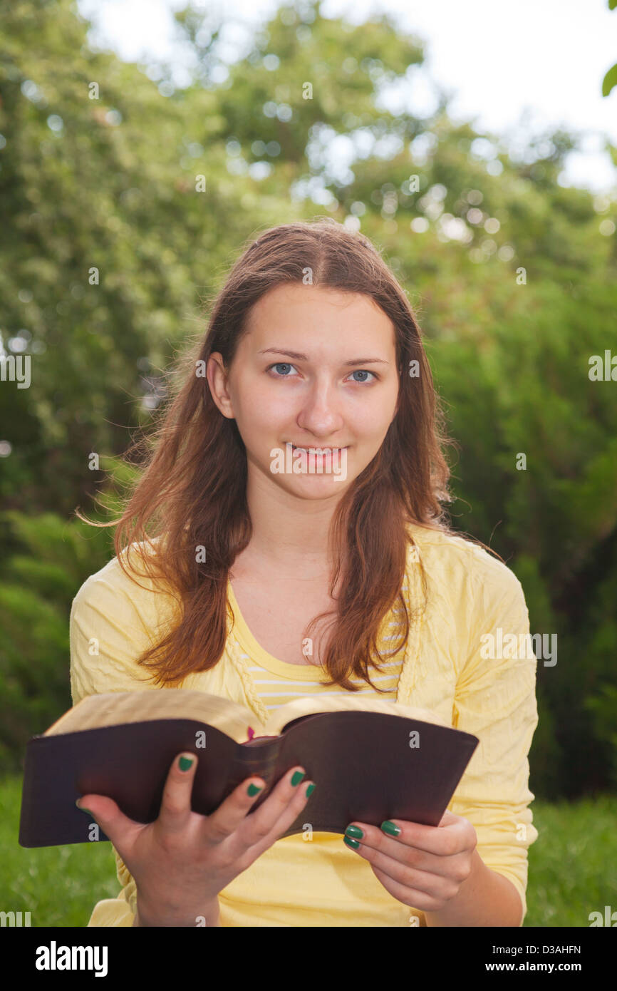 Teen girl reading book à l'extérieur à l'heure d'été Banque D'Images