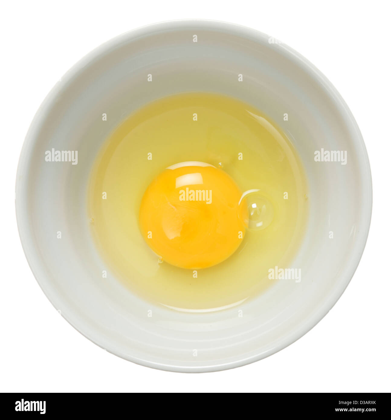 Casse un œuf dans un bol et vu de dessus sur un fond blanc. Banque D'Images