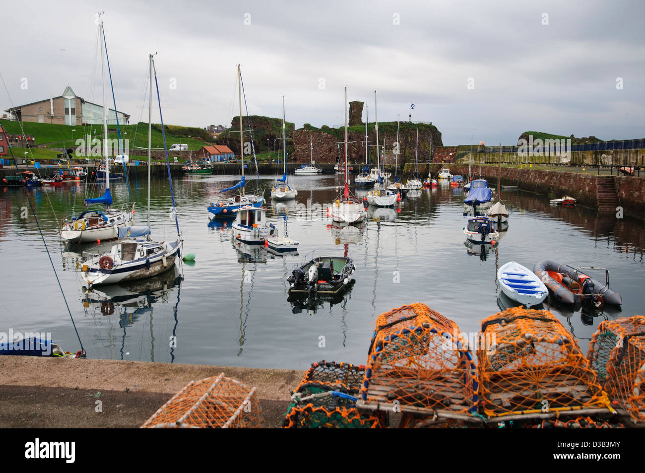 Une vue de Dunbar port avec des casiers à homard à l'avant-plan et Dunbar Castle dans l'arrière-plan. Dunbar, East Lothian, Scotland Banque D'Images