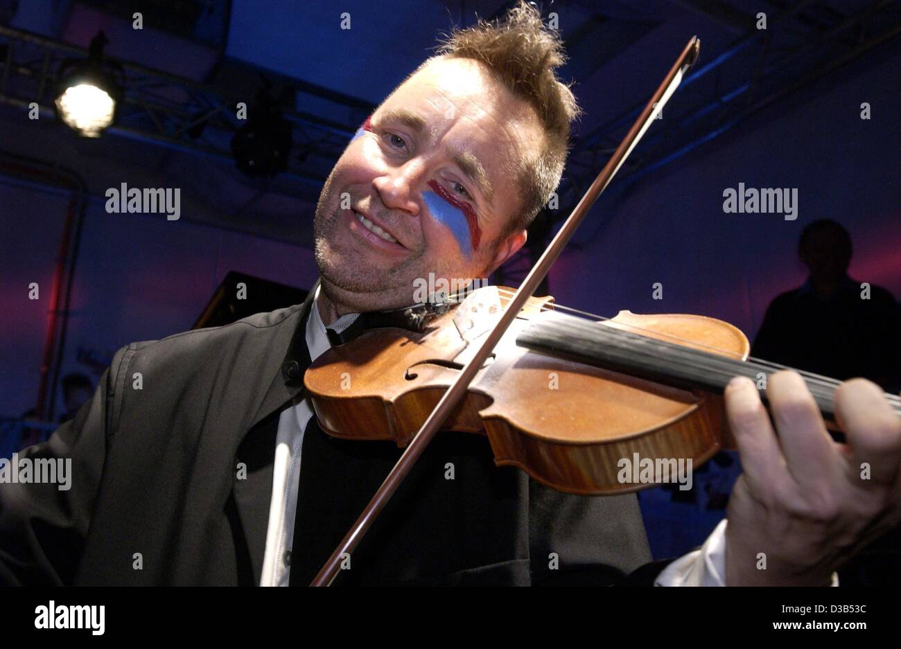 (Afp) - La violoniste Nigel Kennedy a peint son visage aux couleurs de la British Premier-League Club Aston Villa et joue du violon dans un garage souterrain à Cologne, 25 septembre 2002. Le musicien excentrique a présenté son CD actuel "Greatest Hits". En automne il va partir en tournée wi Banque D'Images