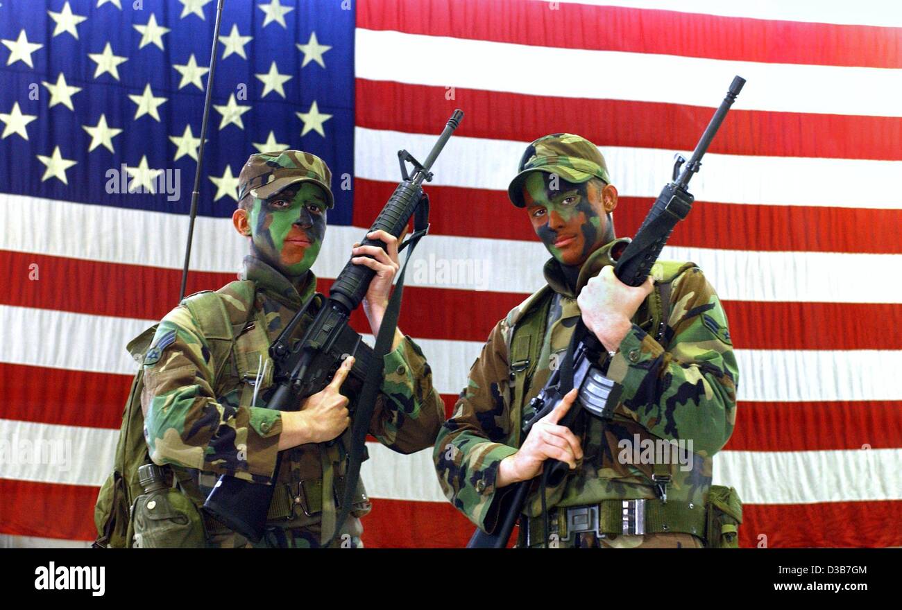 (Afp) - Deux soldats de la 52e Escadre de chasse de l'US Air Force posent avec leurs fusils d'assaut M-16 en face d'un énorme drapeau sur la base aérienne US en Allemagne, Spangdahlem, 25 octobre 2002. C'est la plus grande aile de l'US air force des États-Unis en Europe, qui a déjà participé à des missions au-dessus de l'Iraq et dans la région de bosn Banque D'Images