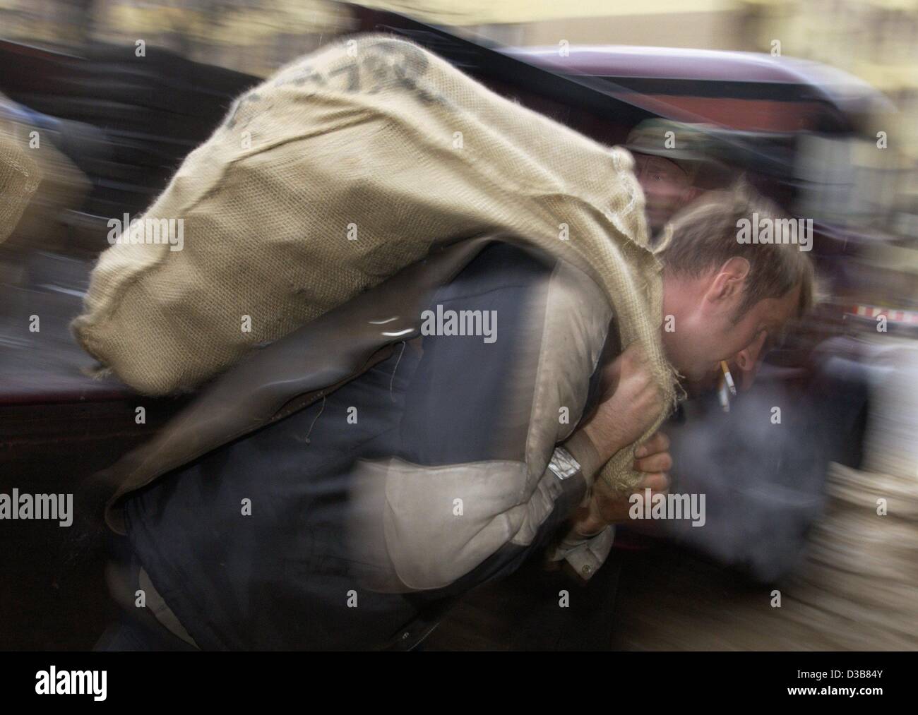 (Afp) - transporteur de charbon Dirk Koegler est porteur d'un sac rempli de charbons ardents sur son dos, Berlin, 6 décembre 2002. Koegler travaille pour un marchand de charbon qui livre environ cinq tonnes de charbon chaque jour, principalement aux ménages privés. Le nombre de marchands de charbon à Berlin est tombé de 900 à 40 au cours des dernières an Banque D'Images