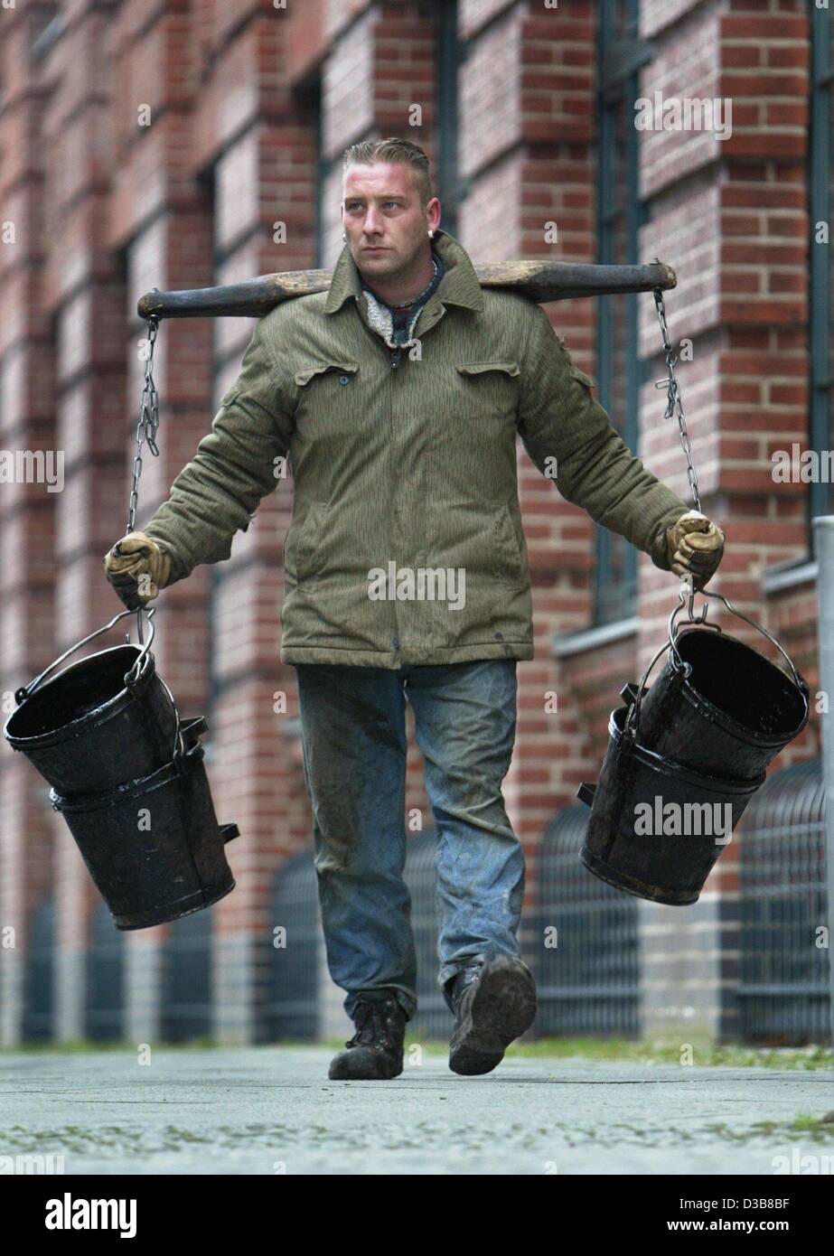 (Afp) - Le bon vieux joug est toujours en usage dans ces temps modernes - Marcel Feuerherd travailleur l'utilise pour transporter quatre seaux de goudron vide sur un chantier à Berlin, 5 décembre 2002. Banque D'Images