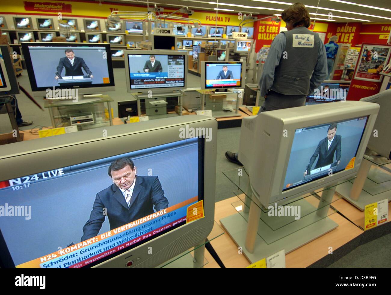 (Afp) - Un client d'un escompteur d'électronique surveille le session du Bundestag concernant le vote de confiance pour le chancelier allemand Gerhard Schroeder sur plusieurs écrans à Hambourg, Allemagne, 1 juillet 2005. Banque D'Images