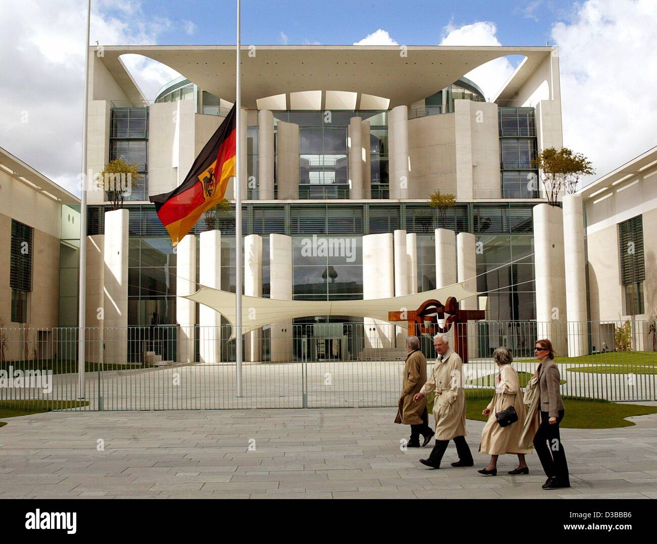 (Afp) - Les gens passent devant la chancellerie à Berlin où le drapeau est mis en berne, Berlin, 27 avril 2002. Le gouvernement a ordonné les drapeaux de tous les édifices publics être baissé après le massacre de 16 personnes et leur agresseur dans une école d'Erfurt. Banque D'Images