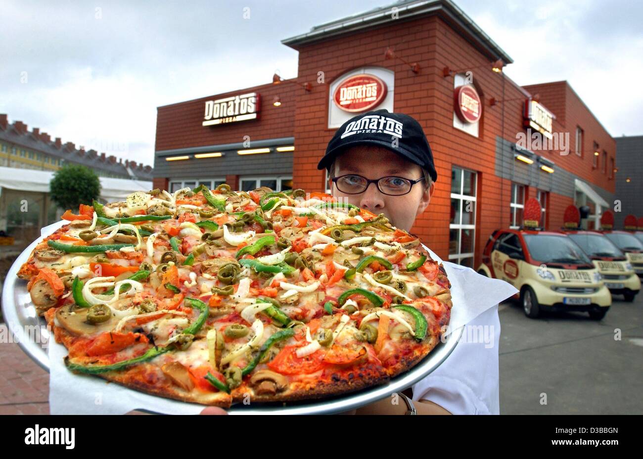 Afp) - Un employé de la chaîne pizza onatos «' se place en avant de la  première filiale allemande à Munich et présente une pizza, 6 novembre 2002.  La plus grande entreprise