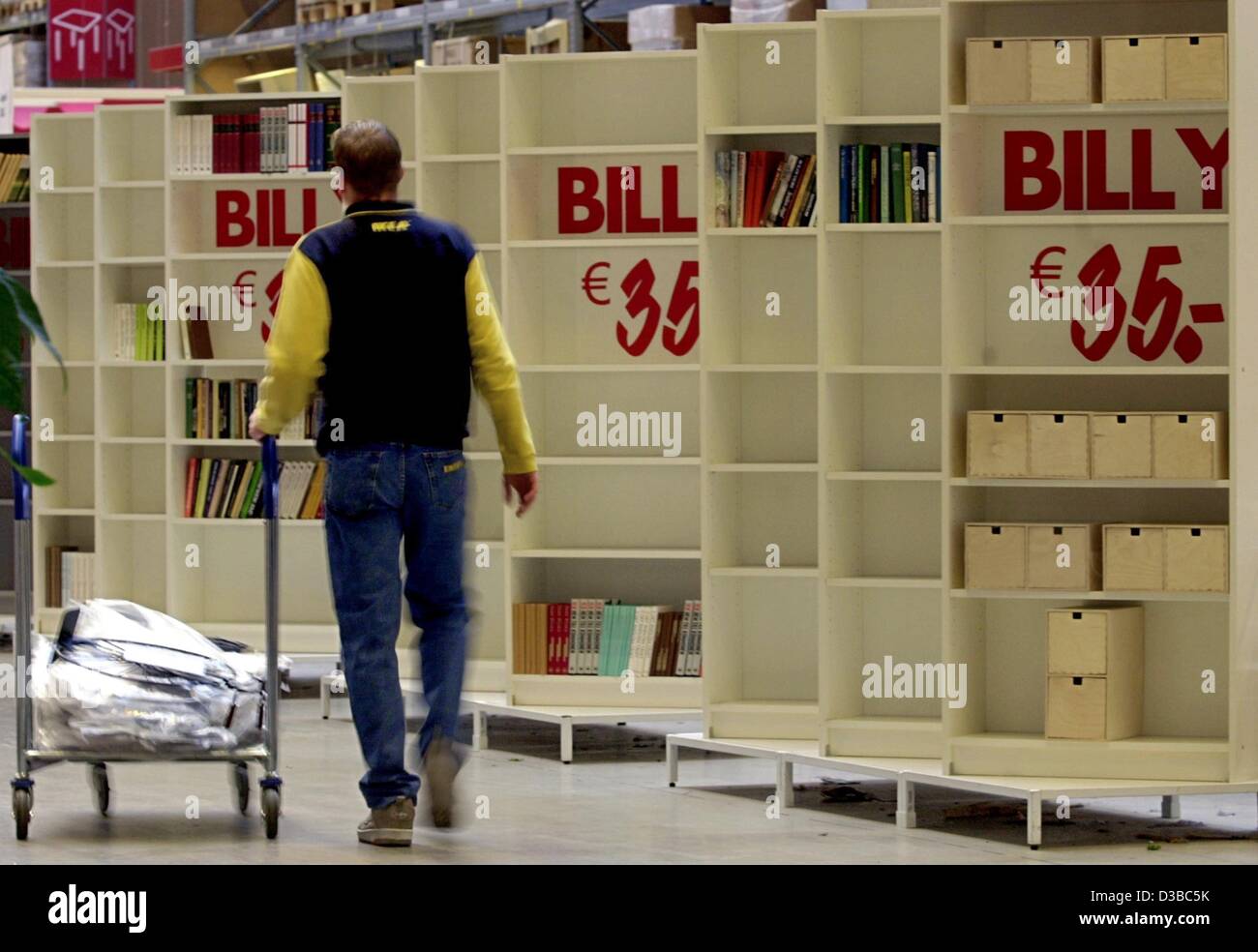 (Afp) - Un employé de la société d'ameublement suédois IKEA pousse un panier au-delà de sa tablette à succès 'Billy' en Allemagne, Wallau, 17 octobre 2002. La chaîne de meubles prévoit une augmentation du chiffre d'affaires de jusqu'à 5 pour cent en 2003 malgré la morosité des consommateurs. Chef allemand Weber parlant en F Banque D'Images