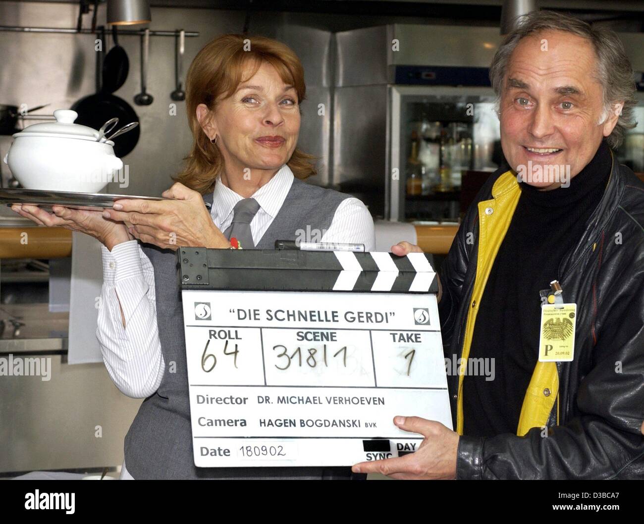 (Afp) - le réalisateur allemand Michael Verhoeven tient dans ses mains un clap tandis que son épouse, l'actrice autrichienne Senta Berger, pose avec un bol de soupe dans son rôle de Gerdi pendant le tournage de 'Die Schnelle Gerdi' (fast Gerdi) à Berlin, le 18 septembre 2002. Verhoeven dirige sa femme dans six nouveaux ep Banque D'Images