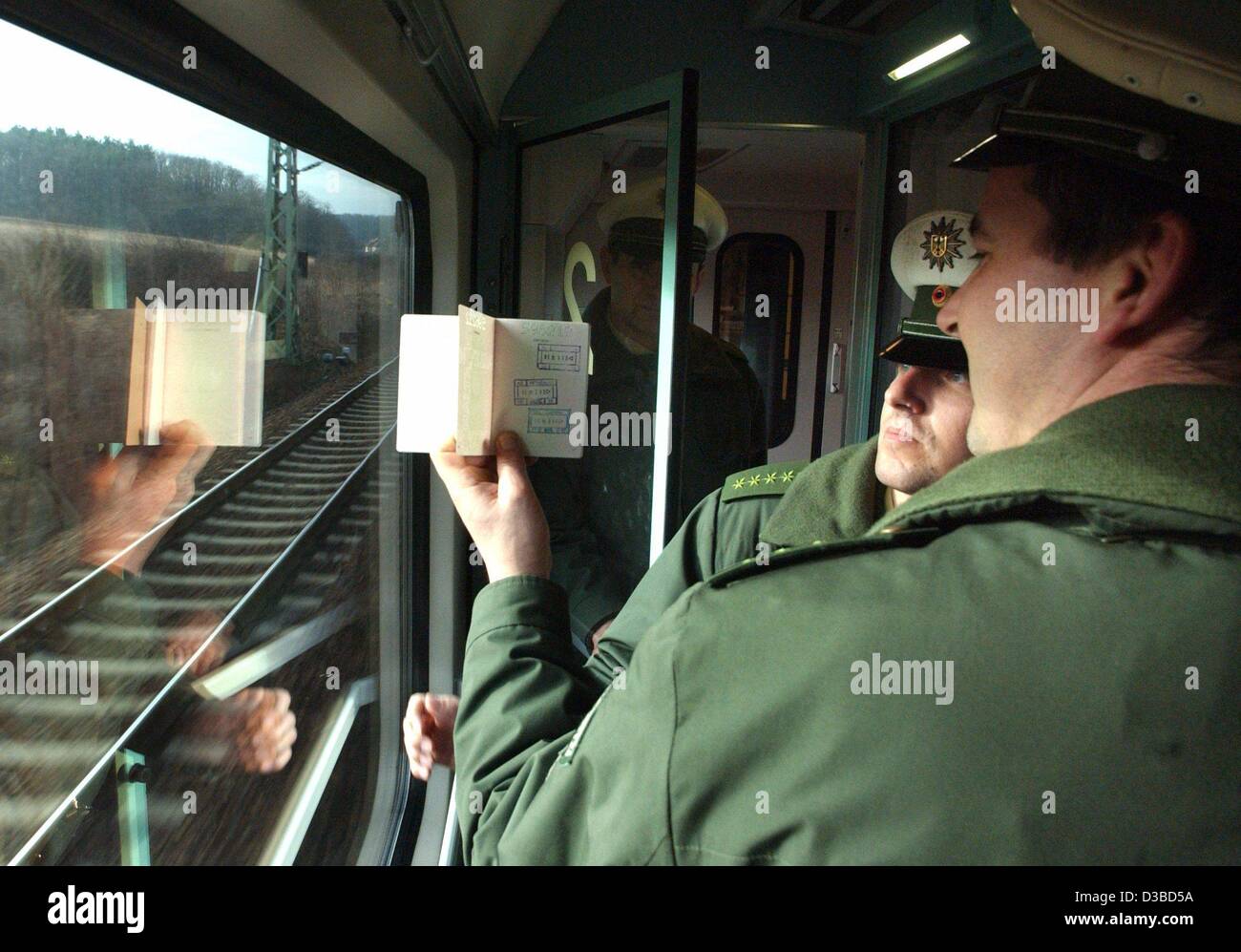 (Afp) - Les agents de la police fédérale des frontières (Bundesgrenzschutz, BGS) vérifier le passeport d'un voyageur dans un train de Varsovie à Berlin, 21 janvier 2003. Le BGS est une police fédérale relevant directement du ministère de l'Intérieur. Il est responsable de la sécurité en Allemagne et couvre une frontière Banque D'Images