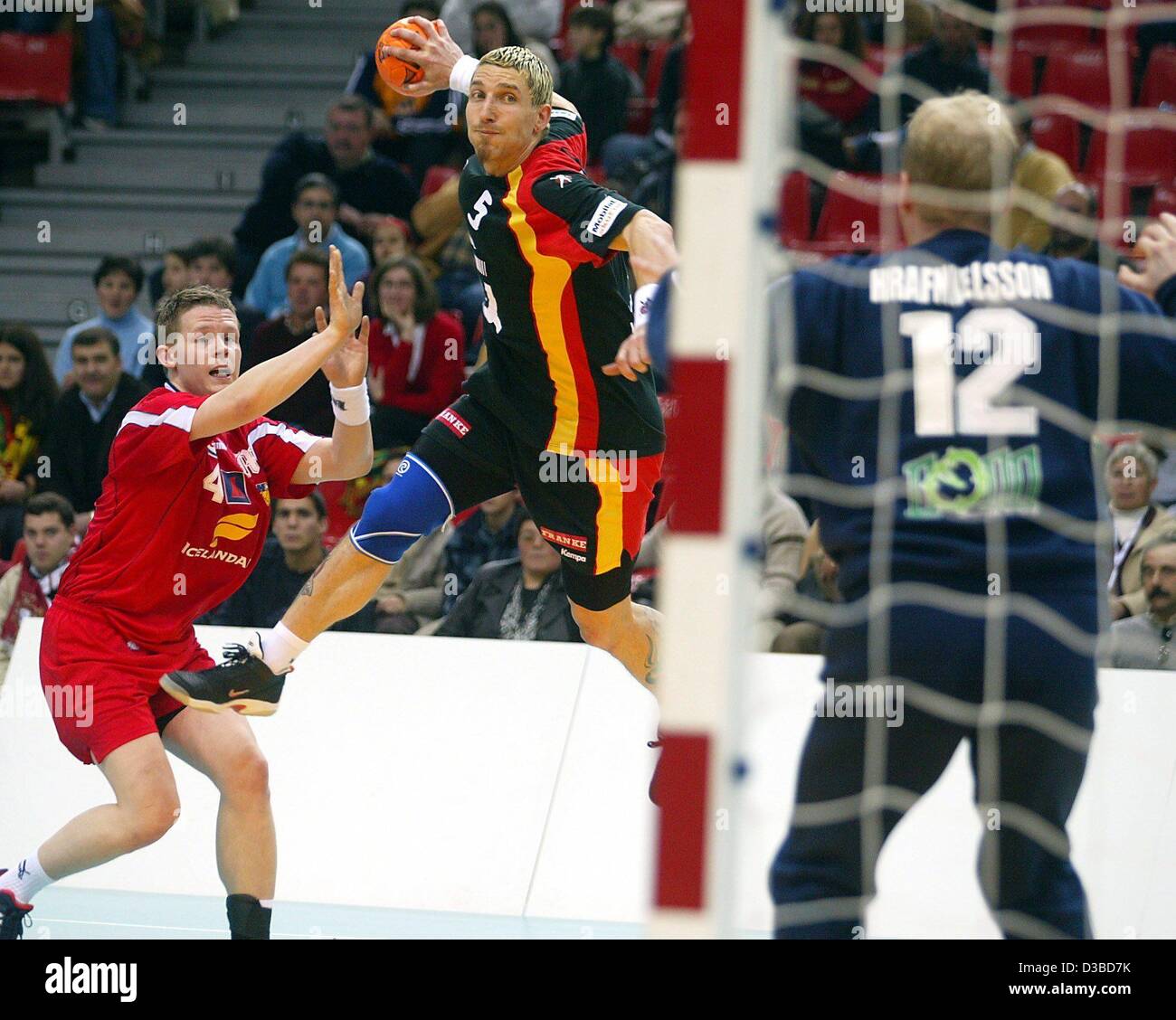 (Afp) - Stefan Kretzschmar ailier de l'Allemagne (L) saute à lancer la balle passé le gardien islandais Gunnar Hrafnkelsson et marque un but lors de la dernière ronde préliminaire du Championnat du Monde de Handball à Viseu, Portugal, 26 janvier 2003. Sur le côté gauche de l'Islande Ole Einar Jonsson. L'allemand Banque D'Images