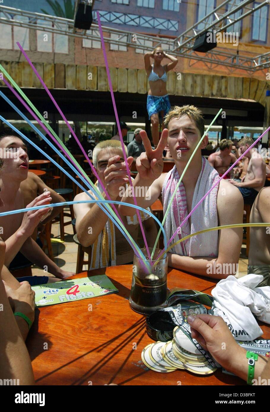 (Afp) - Un groupe de vacanciers se tenir autour d'une table et boire dans un grand verre à la paille pendant que l'un d'entre eux le symbole de la paix des gestes à la 'Méga-park' dans la barre de Ballermann le long de la promenade à El Arenal près de Palma sur l'île de Majorque, Espagne, le 5 juin 2003. Majorque est la plus grande o Banque D'Images