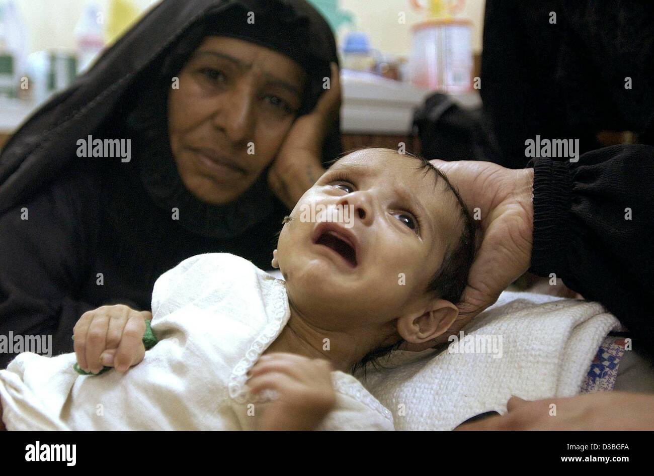 (Afp) - un enfant souffrant de déshydratation est réconforté par les membres de la famille dans un hôpital dans le centre-ville de Bagdad, 18 mai 2003. La pollution de l'eau n'est toujours la raison de la mort de nombreux enfants irakiens. Banque D'Images