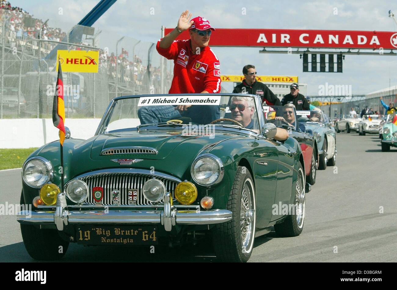 (Afp) - L'allemand champion du monde de Formule 1 Michael Schumacher (Ferrari) est assis sur le dos d'une Austin-Healey oldtimer et accueille est lors de la parade des pilotes sur le circuit Gilles Villeneuve de formule 1, avant le début de piste Grand Prix du Canada à Montréal, Canada, 15 juin 2003. Banque D'Images