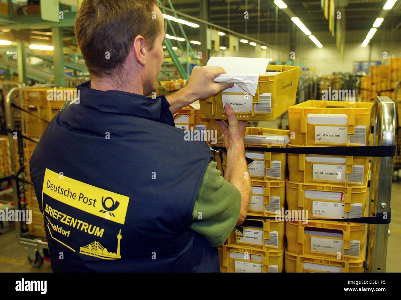 (Afp) - Un employé de la Deutsche Post AG décharge un panier avec des bacs jaunes à la lettre post centre (Briefzentrum) à Düsseldorf, Allemagne, le 27 janvier 2003. L'entreprise dispose de 83 centres courrier national et un poste international centre. Chaque jour environ 72 millions de lettres sont triées et envoyées par la poste. Banque D'Images